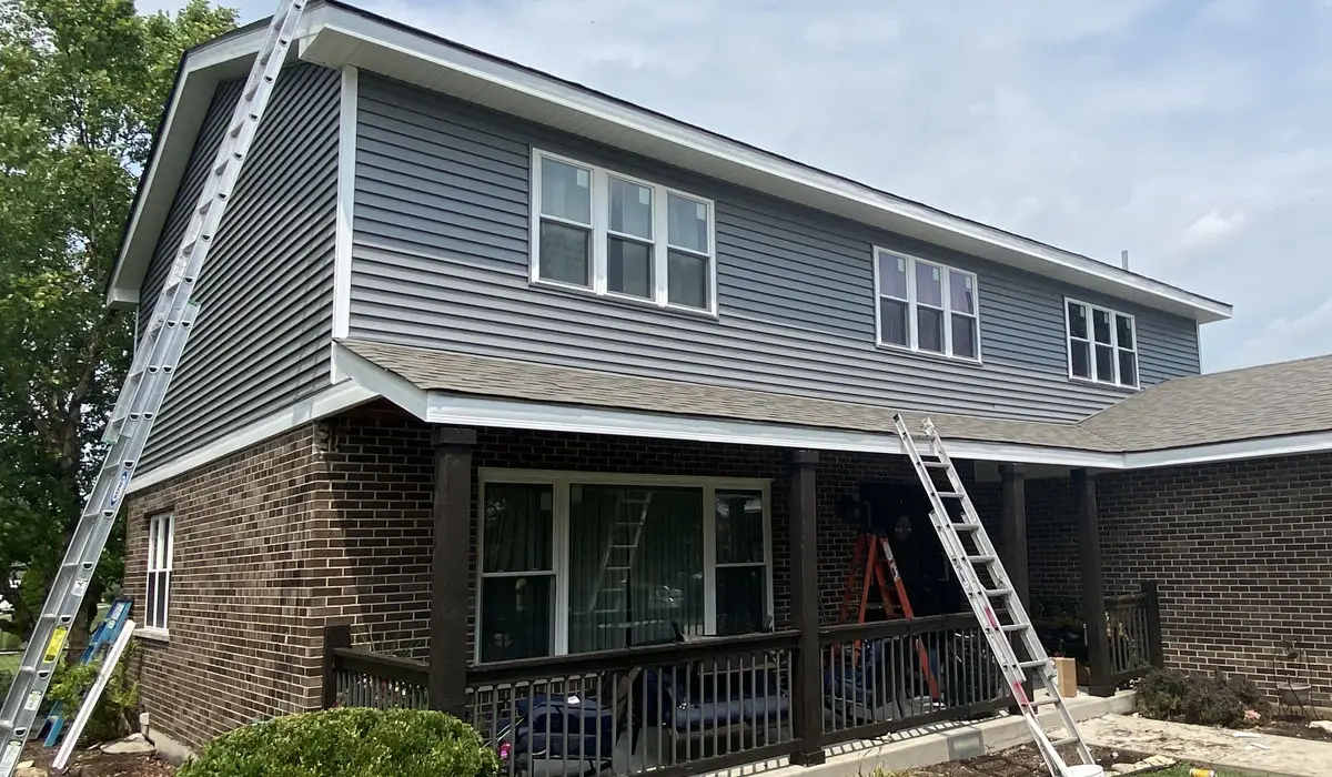 Two ladders leaned on a two-storey house reaching the gutters. Home exterior remodeling.