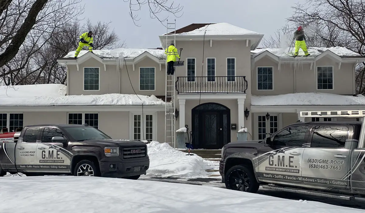 Roofing contractors removing ice dam from roof. Winter roof care by Greater Midwest Exteriors.